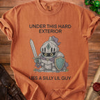 Orange shirt with a cartoon knight graphic and text "Under This Hard Exterior Lies A Silly Lil Guy".