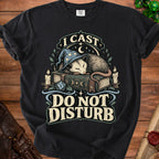 Black t-shirt featuring an opossum in a wizard hat sleeping on a spellbook with text reading I CAST DO NOT DISTURB.