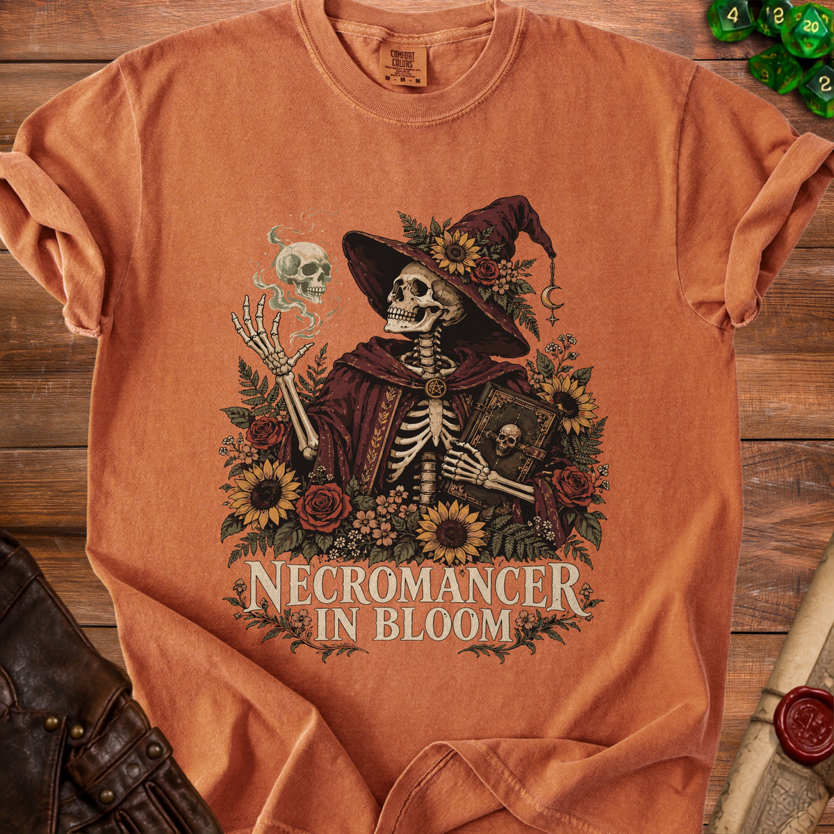 Skeleton necromancer with a book and skull, surrounded by flowers, with text "NECROMANCER IN BLOOM".