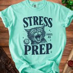 Mint green t-shirt with a distressed graphic of a screaming cat, dice, and text "STRESS COUNTS AS PREP".