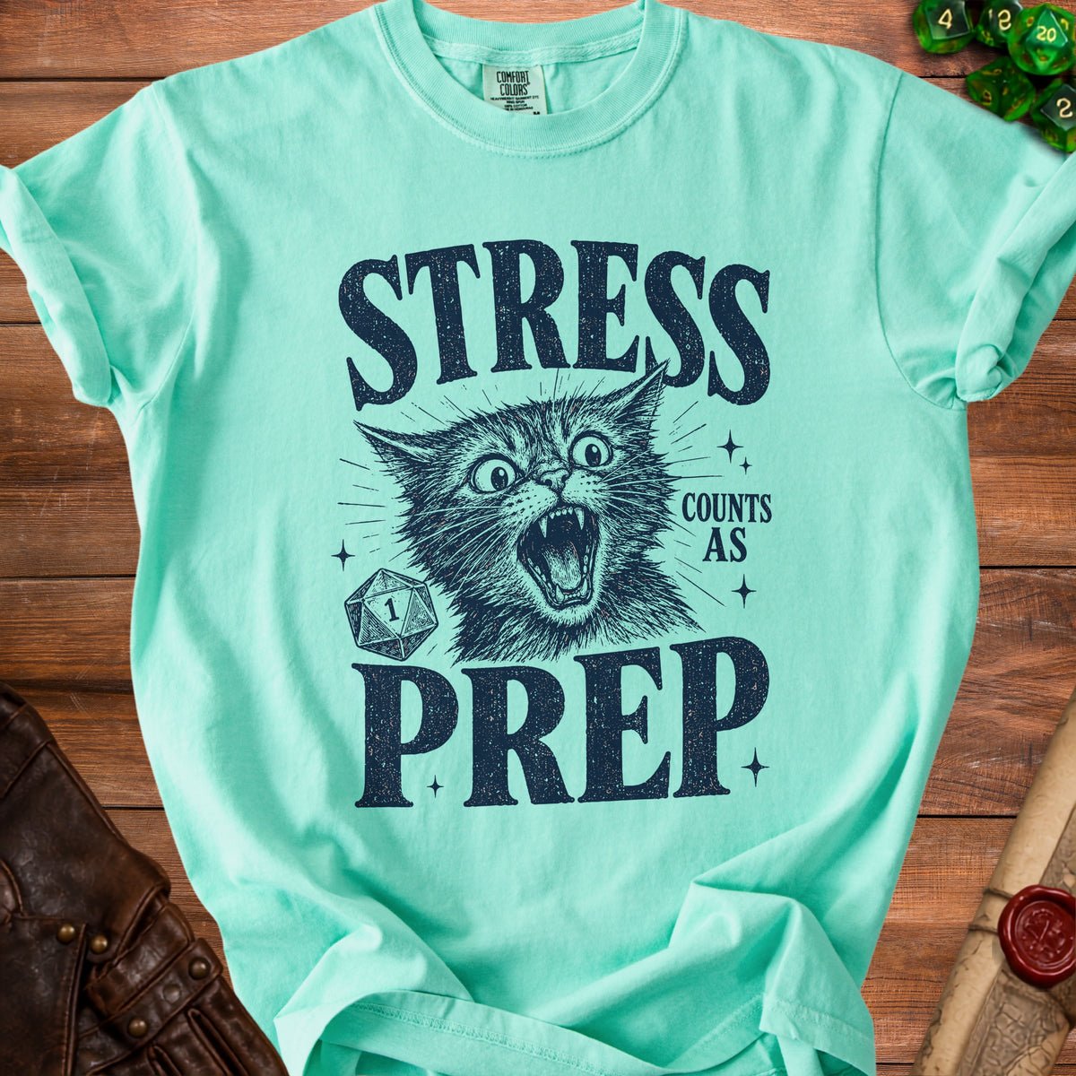 Mint green t-shirt with a distressed graphic of a screaming cat, dice, and text "STRESS COUNTS AS PREP".