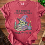 Red t-shirt with skull wearing wizard hat, stack of books, candle, and potion. "Too tired to prepare spells will wing it" text.