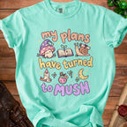Teal t-shirt with "my plans have turned to mush" text and whimsical illustrations.