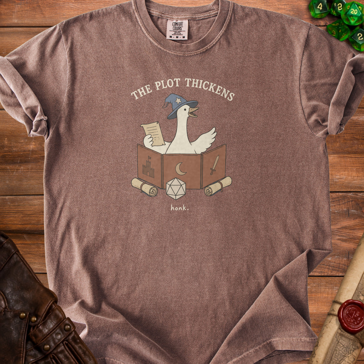 T-shirt with white goose wearing wizard hat and reading a scroll; text: "The Plot Thickens honk."