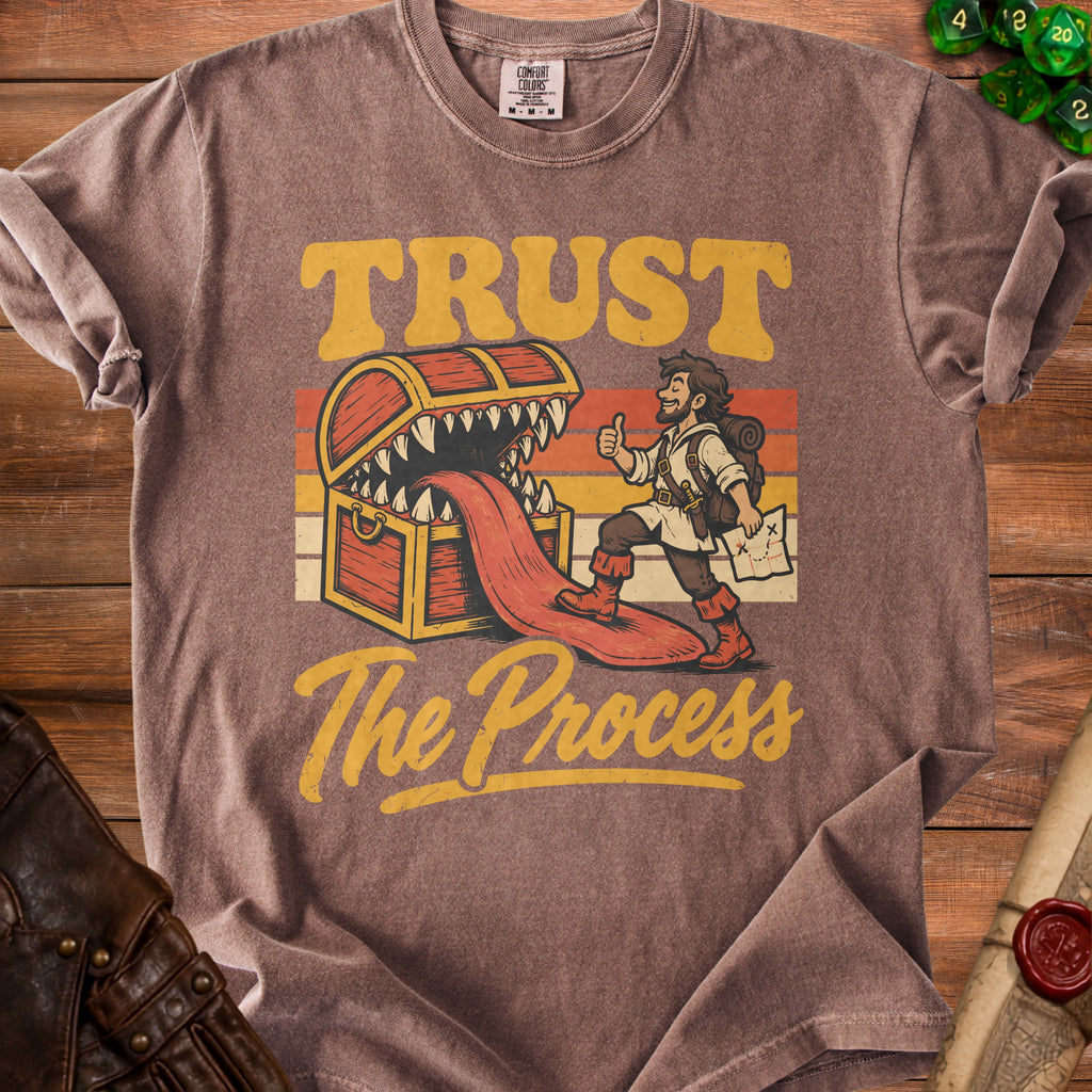 Brown t-shirt with adventurer, treasure chest, and text "TRUST The Process".