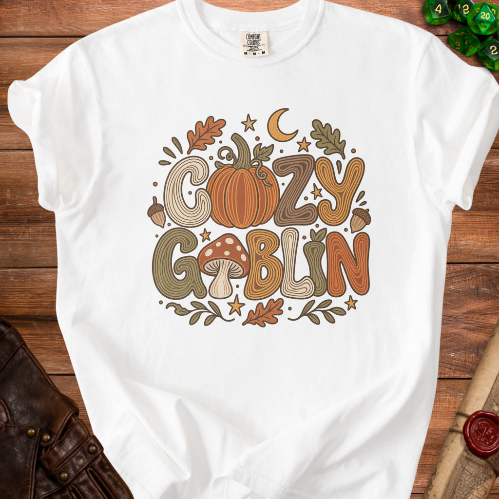 White t-shirt with "Cozy Goblin" text and fall-themed illustrations.