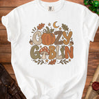 White t-shirt with "Cozy Goblin" text and fall-themed illustrations.