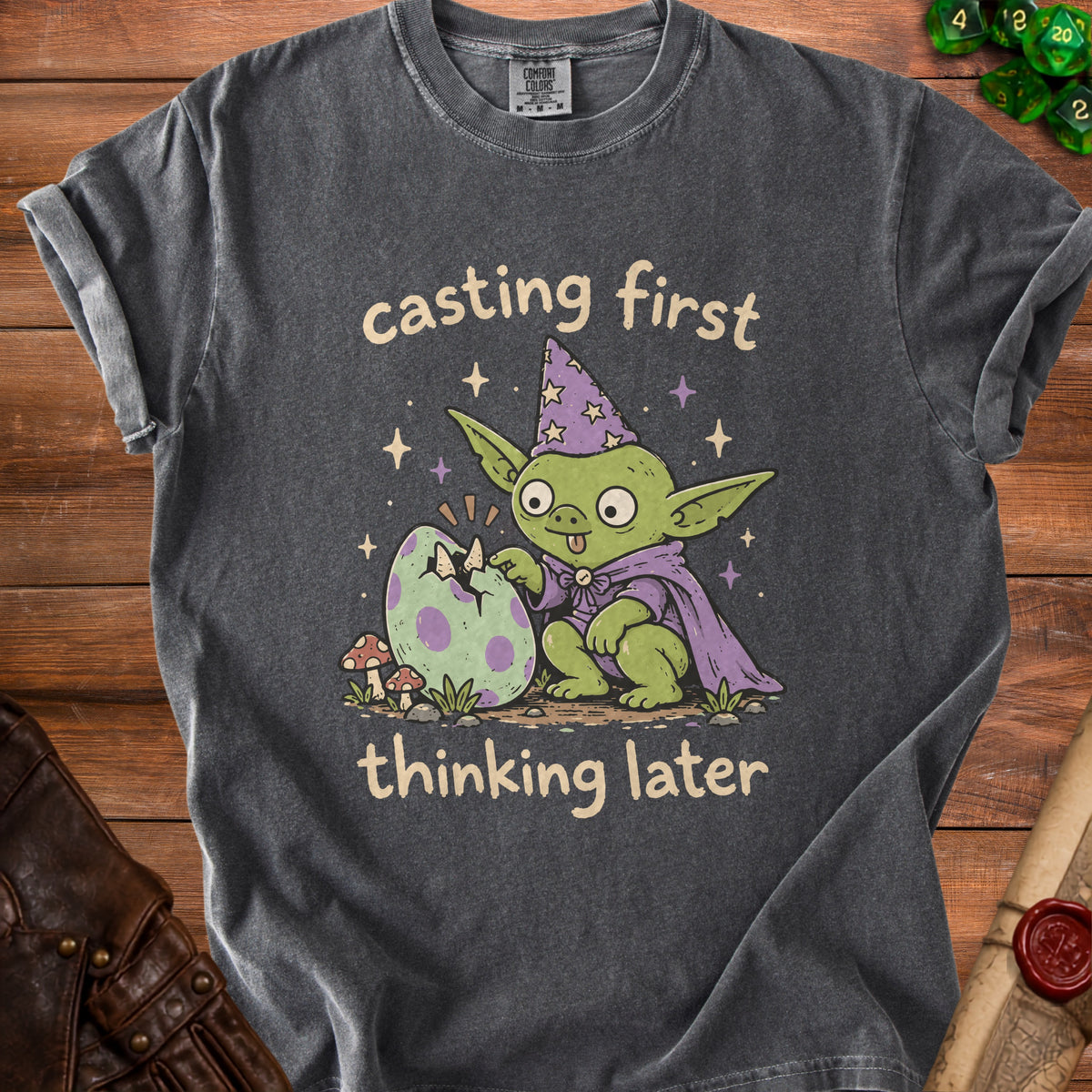 Dark t-shirt with graphic of a goblin hatching an egg, text "casting first thinking later".