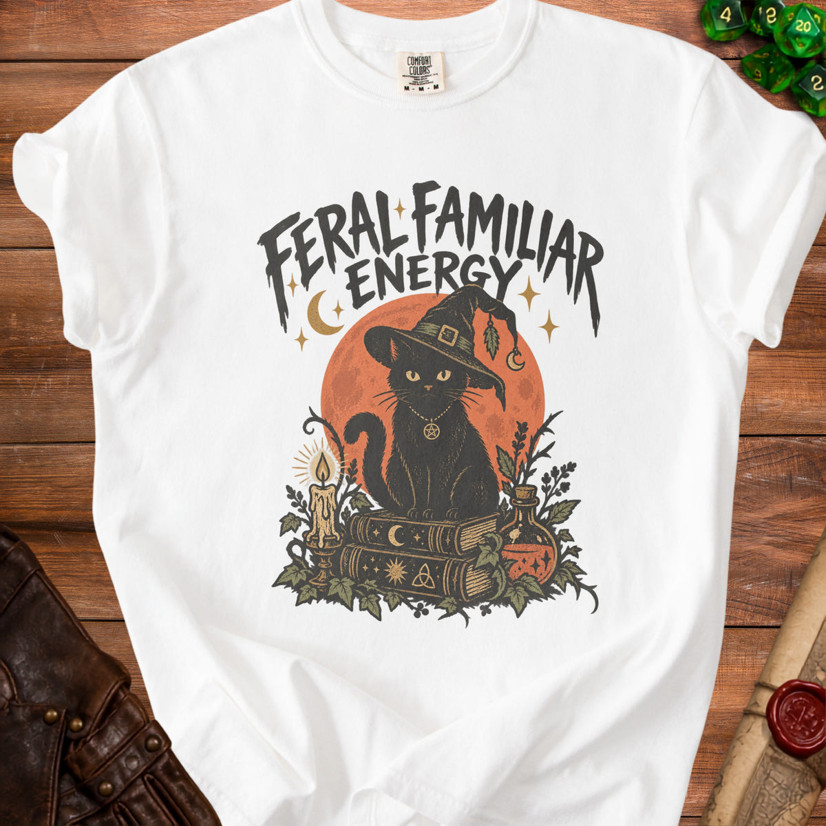 White t-shirt with black cat in witch hat, books, candle, and potion. "FERAL FAMILIAR ENERGY" text.