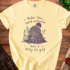 Yellow t-shirt with a knight character and text "Under this hard exterior lies a Silly lil guy".