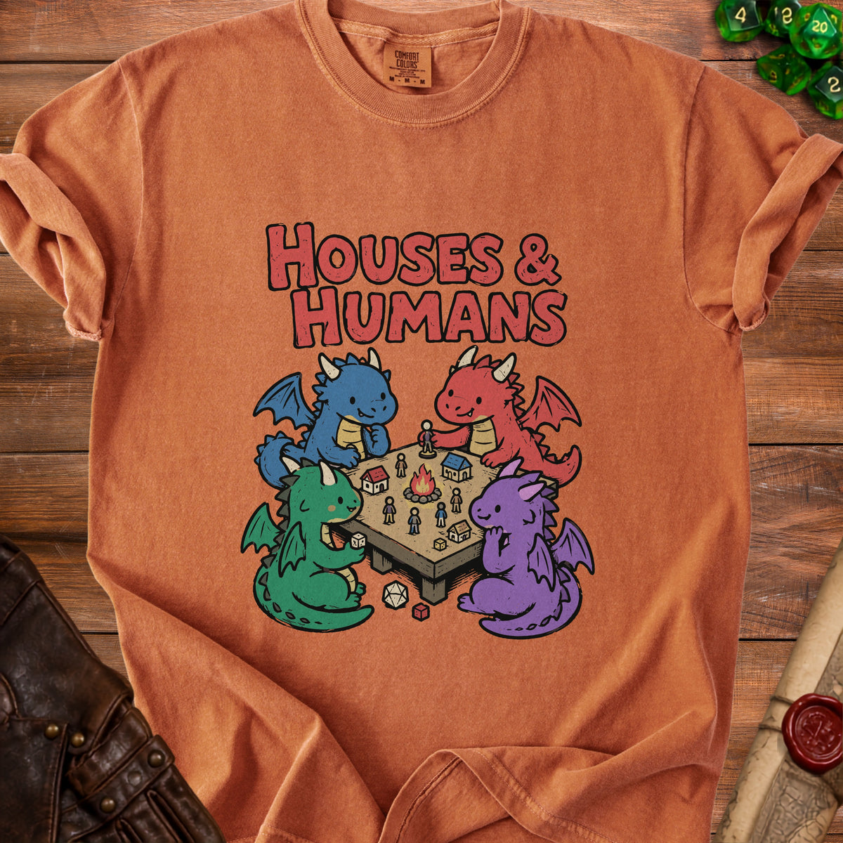 Orange t-shirt with "HOUSES & HUMANS" and cartoon dragons playing tabletop game.