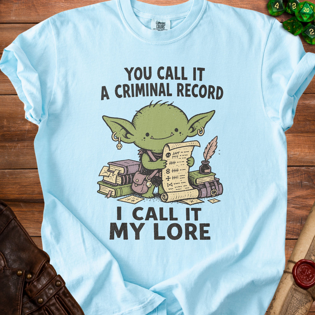 Light blue t-shirt with a goblin illustration holding a scroll with tally marks and text.