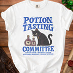 White t-shirt with a black cat and potion bottles, "Potion Tasting Committee" text.