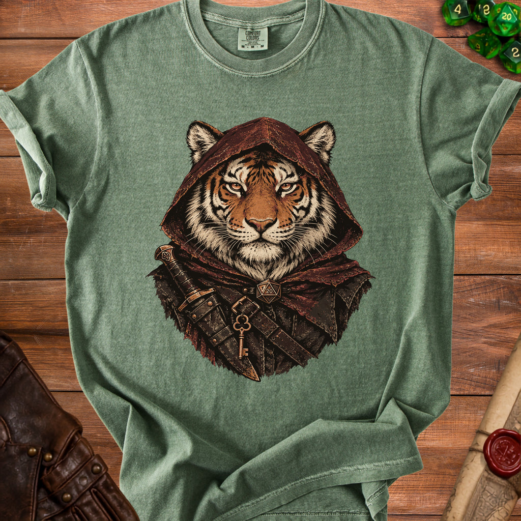 Green t-shirt featuring a fantasy graphic of a tiger wearing a hood and dagger on a wooden surface.