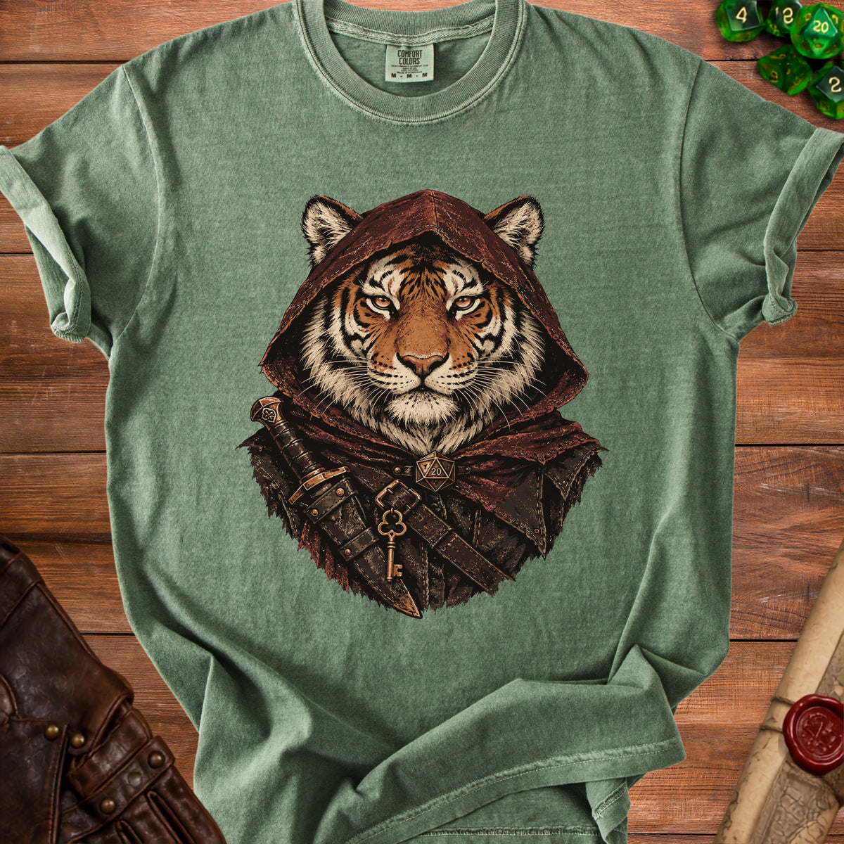 Green t-shirt featuring a fantasy graphic of a tiger wearing a hood and dagger on a wooden surface.