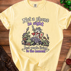 Yellow t-shirt with "Not a phone in sight, Just people living in the moment" text and cartoon knight cat fighting goblins.