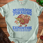 Green t-shirt with mushroom foraging goblin graphic and text "MUSHROOM FORAGING EXPEDITION".