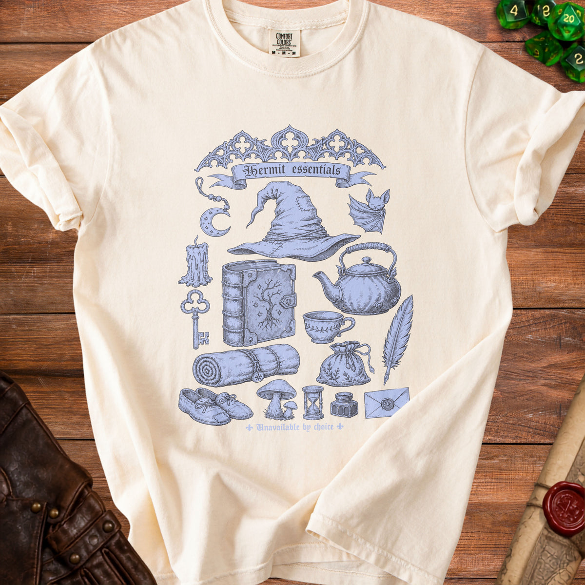 Cream t-shirt with blue "Hermit essentials" graphic including a wizard hat, book, and teacup.