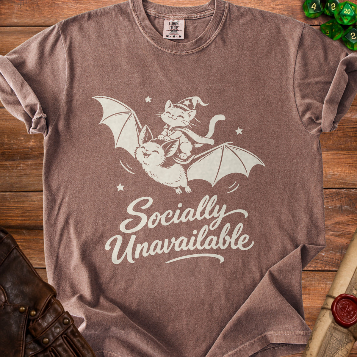 Brown t-shirt with white graphic of a cat riding a bat, reading "Socially Unavailable".