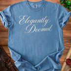 Blue Comfort Colors t-shirt with "Elegantly Doomed" text.