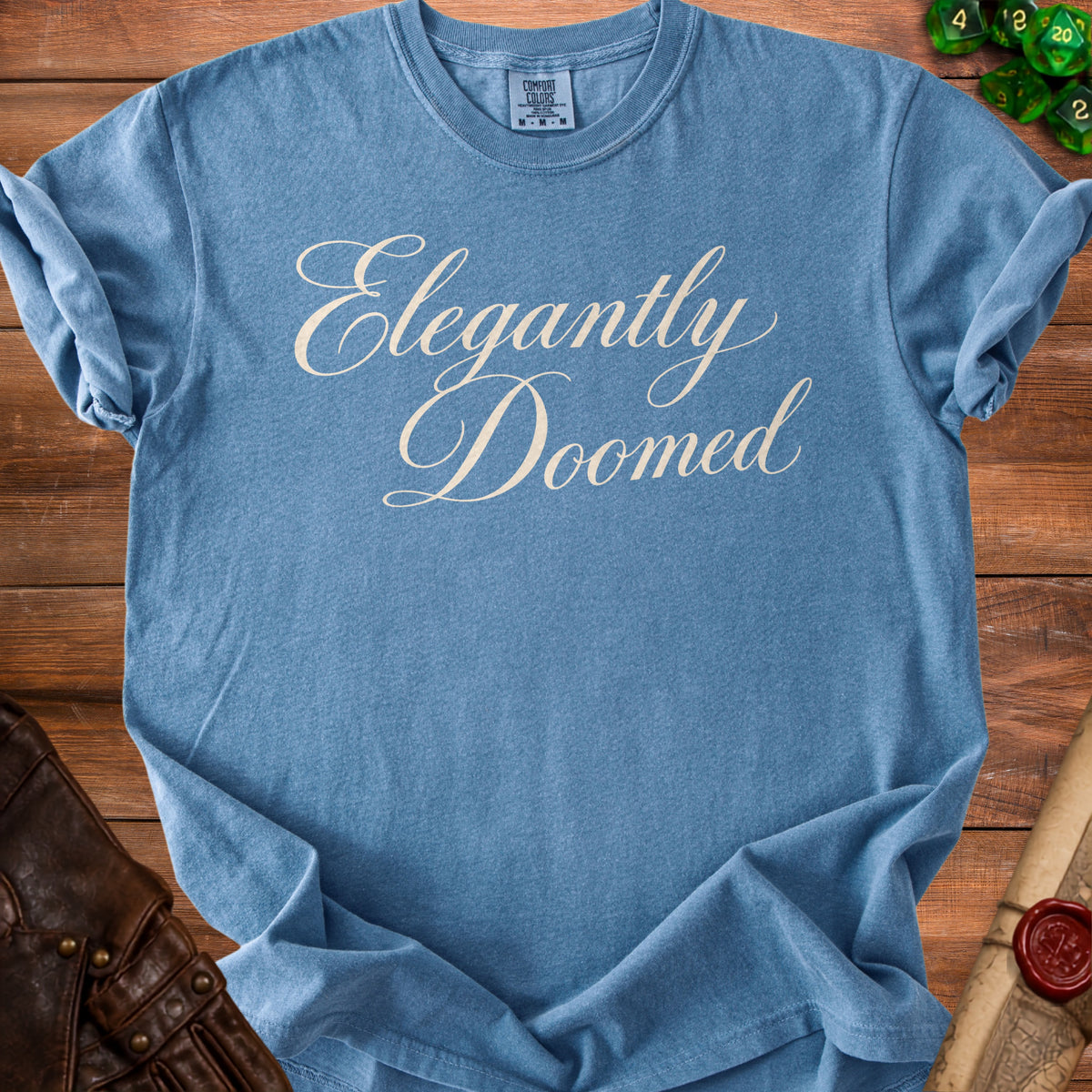 Blue Comfort Colors t-shirt with "Elegantly Doomed" text.