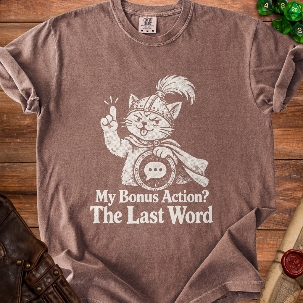 T-shirt with white graphic of a cat wearing a helmet and cape, holding a speech bubble. Text reads: "My Bonus Action? The Last Word."