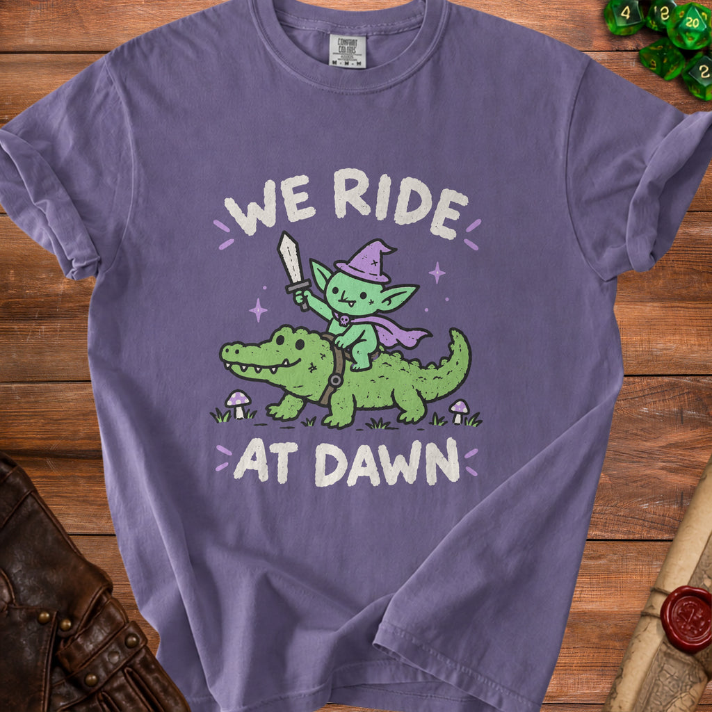 Purple t-shirt with a goblin riding an alligator, reading "WE RIDE AT DAWN".