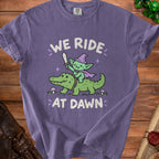 Purple t-shirt with a goblin riding an alligator, reading "WE RIDE AT DAWN".