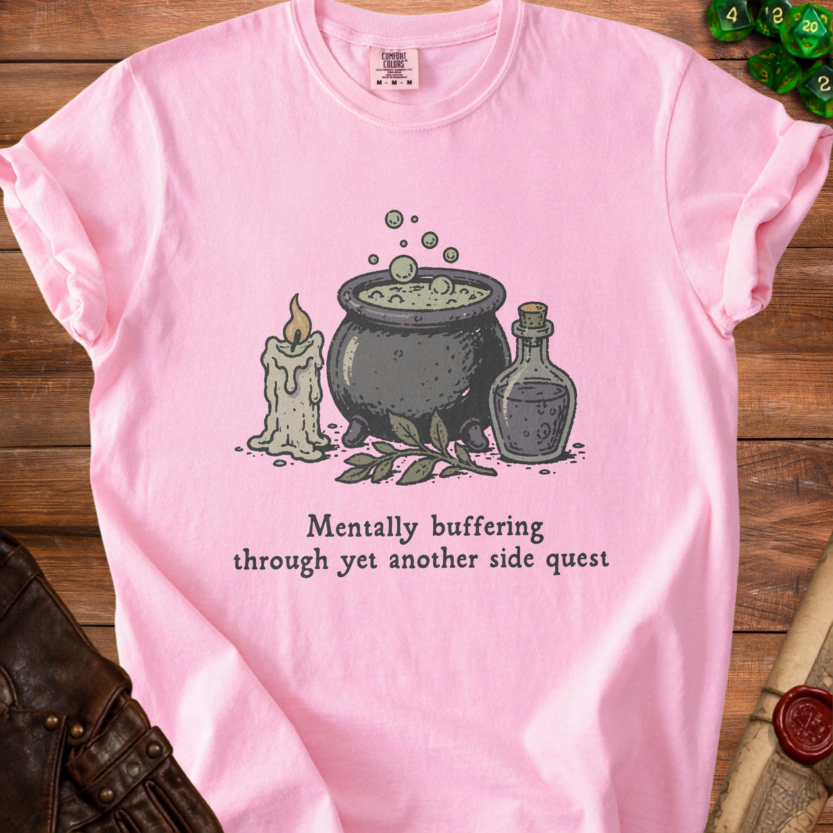 Pink t-shirt with cauldron, candle, potion, and text "Mentally buffering through yet another side quest".