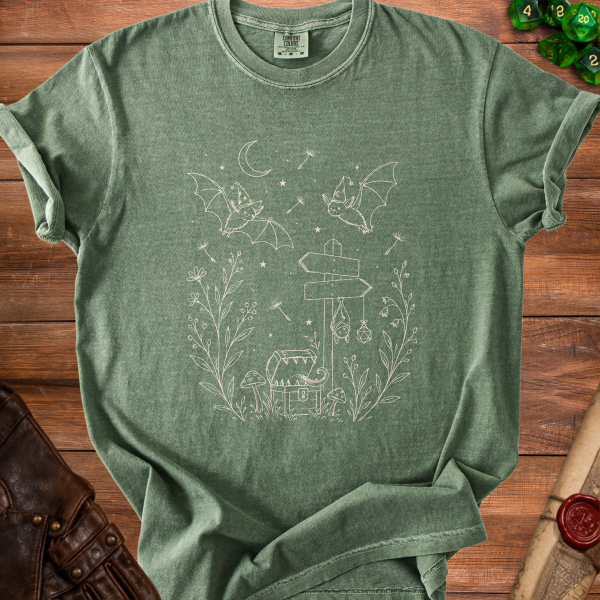 Green t-shirt with line art of bats, chest, mushrooms, and signage.
