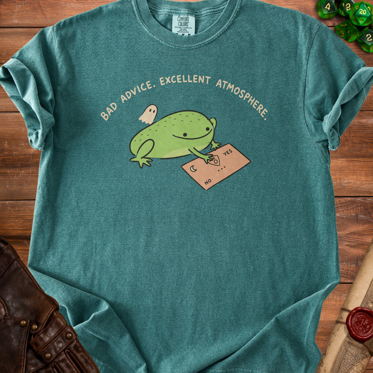 Green t-shirt with a frog, ghost, and ouija board graphic. Text reads "BAD ADVICE. EXCELLENT ATMOSPHERE."