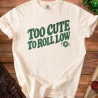 Cream t-shirt with "Too Cute To Roll Low" text and dice graphic.