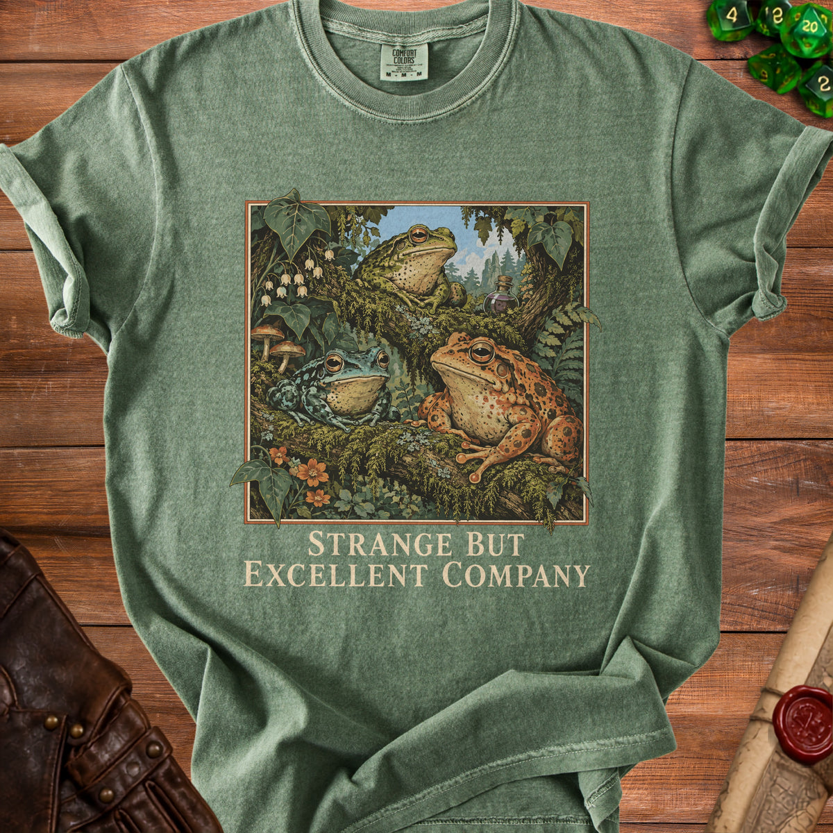 Green t-shirt with three frogs on a branch and text "STRANGE BUT EXCELLENT COMPANY".