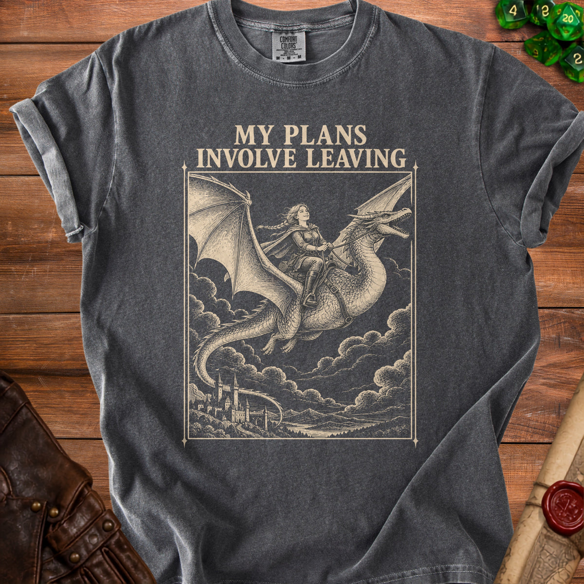 A charcoal gray t-shirt with a vintage-style graphic of a woman riding a dragon above a castle, accompanied by the text "MY PLANS INVOLVE LEAVING."