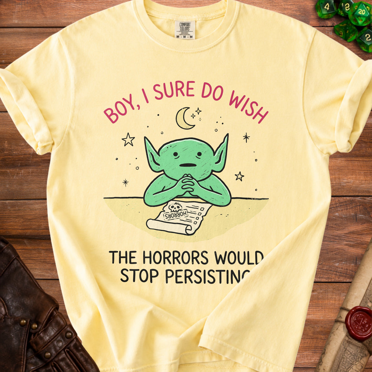 Yellow t-shirt with a green character looking at a scroll that says "HORRORS".