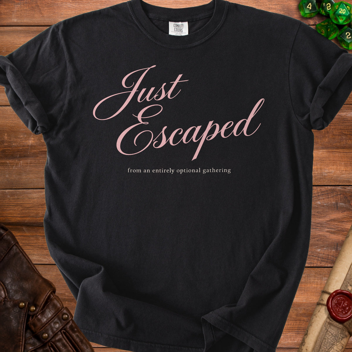 A black t-shirt printed with the pink text Just Escaped from an entirely optional gathering.