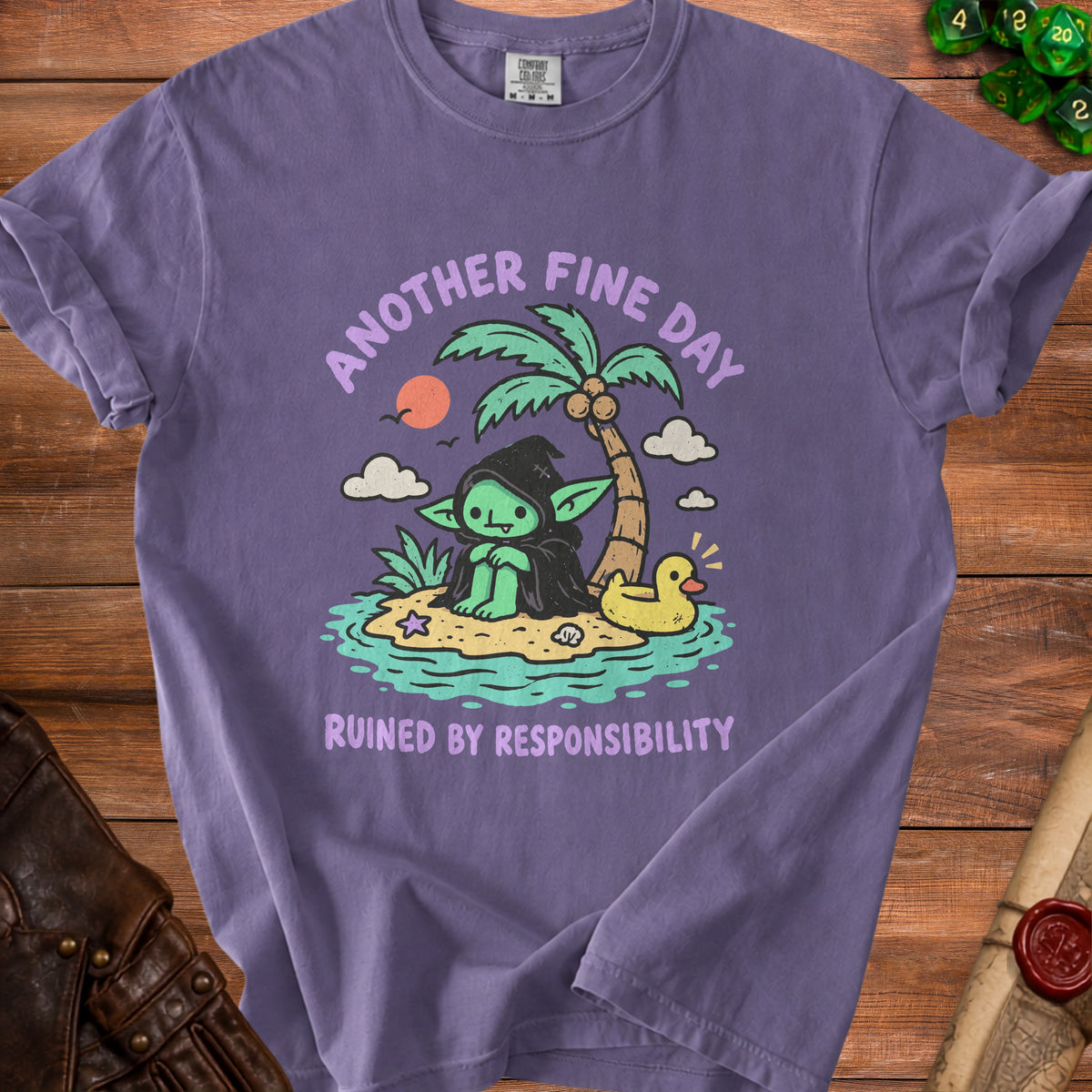 Purple t-shirt with a graphic of a goblin on a beach saying "Another fine day ruined by responsibility."