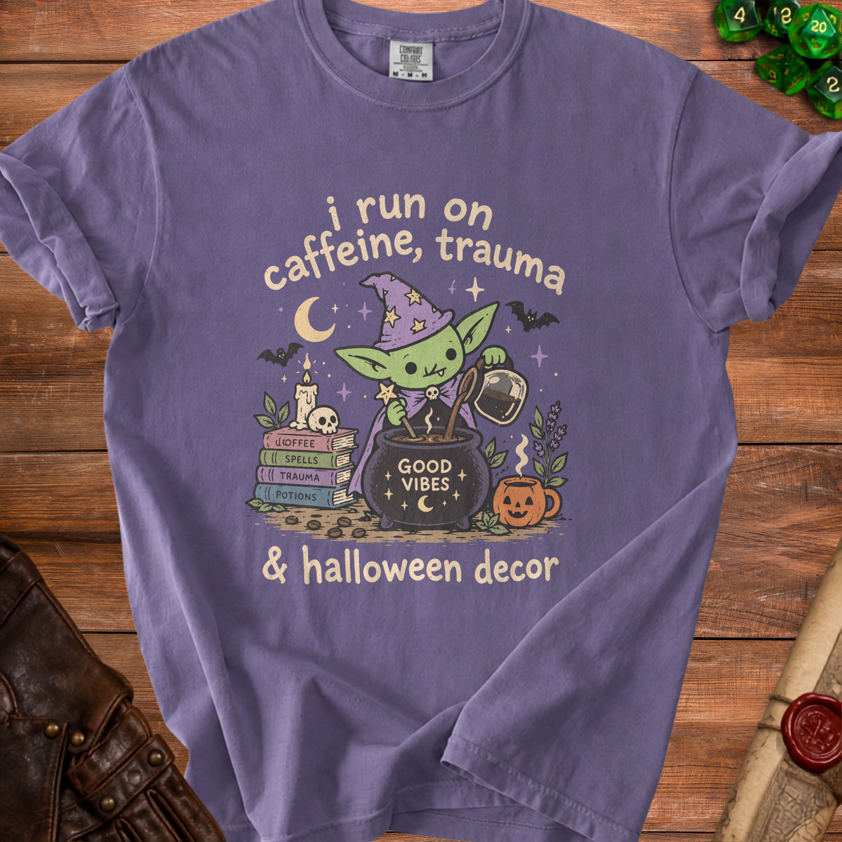 Purple t-shirt with graphic of a goblin witch brewing coffee with text "i run on caffeine, trauma & halloween decor".