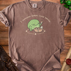 Brown t-shirt with a graphic of a frog and ghost saying "I summoned snacks. Close enough."