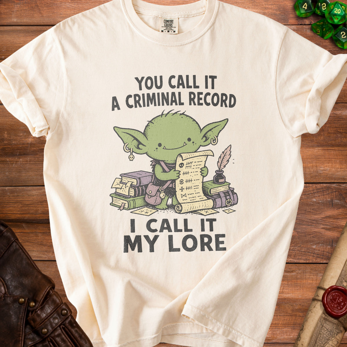 Cream t-shirt with green goblin graphic reading "You call it a criminal record, I call it my lore."