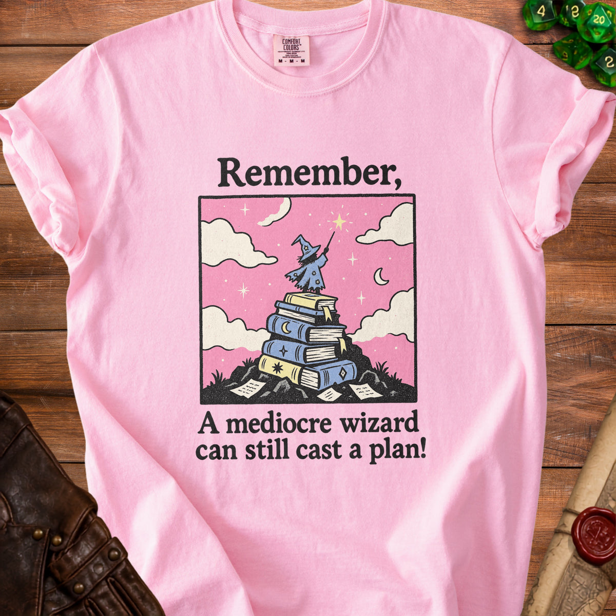 Pink t-shirt with graphic of wizard on books, text "Remember, A mediocre wizard can still cast a plan!"