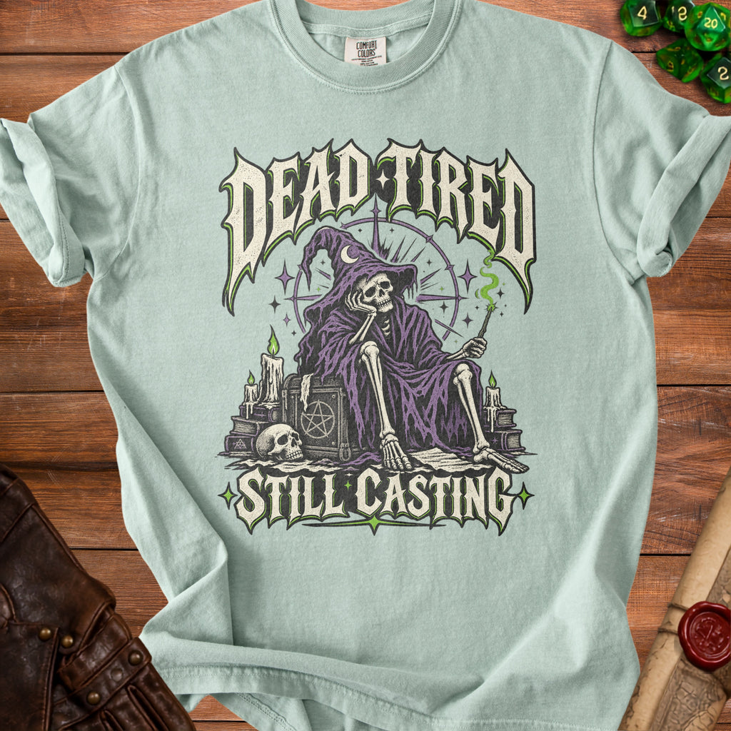 Light blue t-shirt featuring a skeleton wizard with text "DEAD TIRED STILL CASTING."