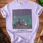 Purple t-shirt with graphic of a wizard by a campfire and text "NOT IGNORING YOU. JUST RECHARGING MY SOCIAL BATTERY."