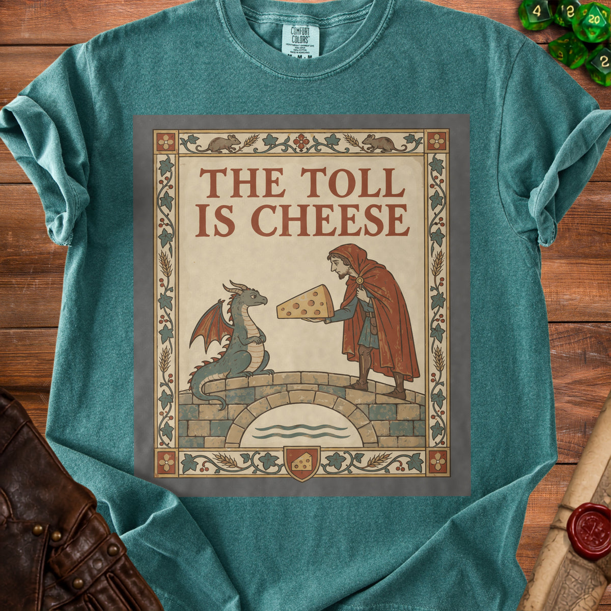 T-shirt graphic: dragon on bridge receiving cheese from a man. Text reads "THE TOLL IS CHEESE".