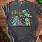 Three cats in armor explore a treasure chest filled with dice and books.