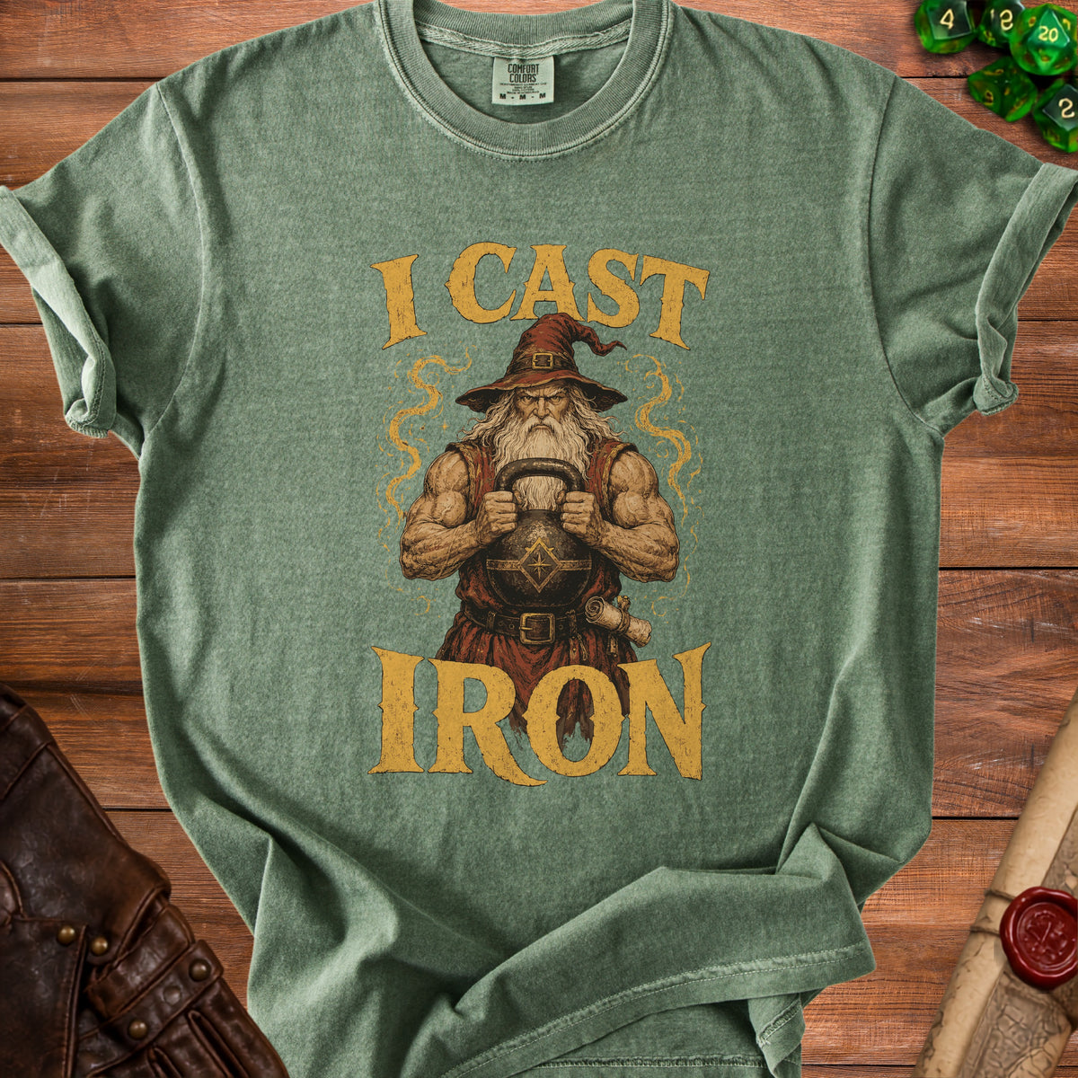 Green t-shirt with illustration of a muscular wizard holding a kettlebell and the words "I CAST IRON".