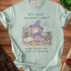 Light green t-shirt with "It's spicy you won't like it" and witch illustration.