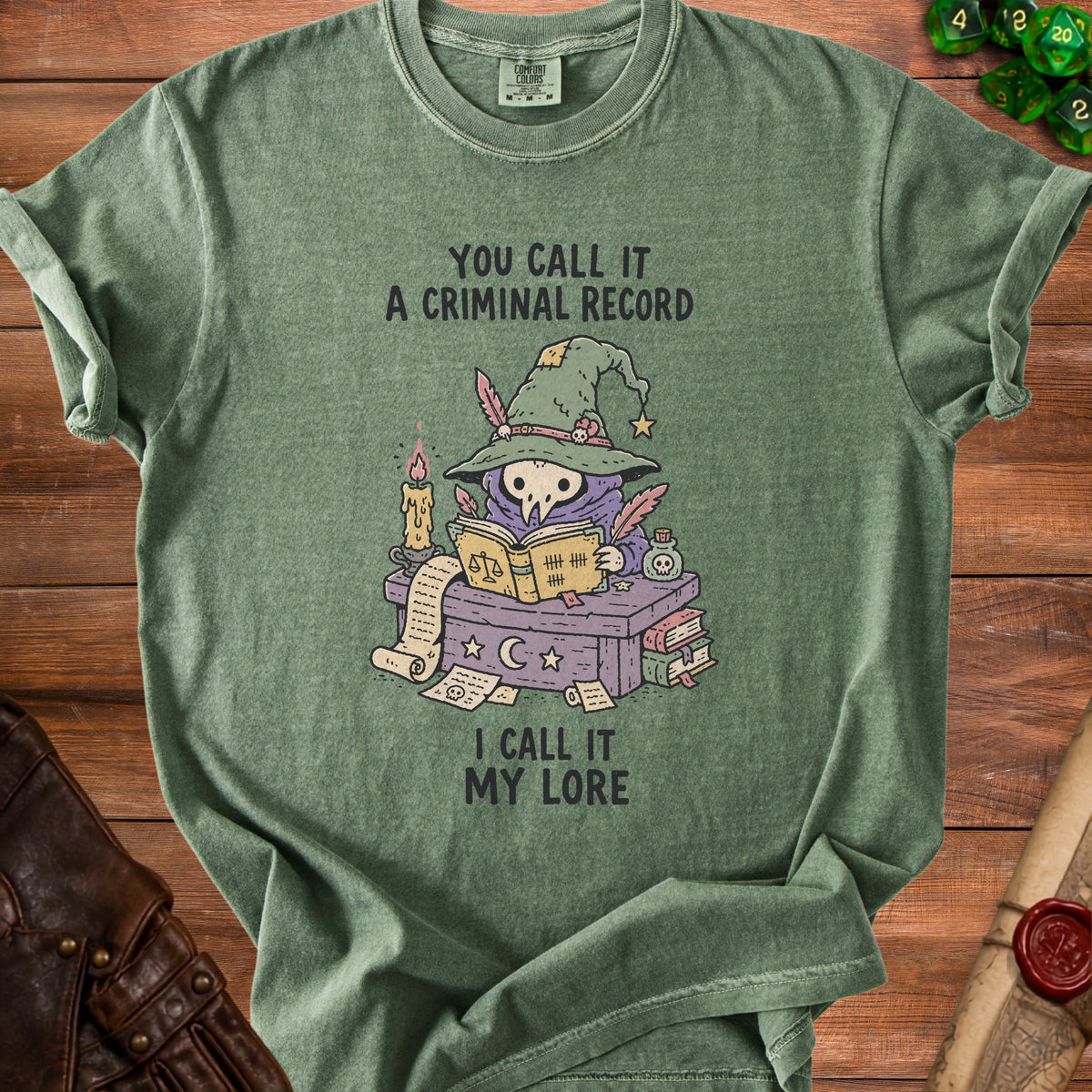 Green t-shirt with cartoon skull in witch hat reading book, text "You call it a criminal record I call it my lore".