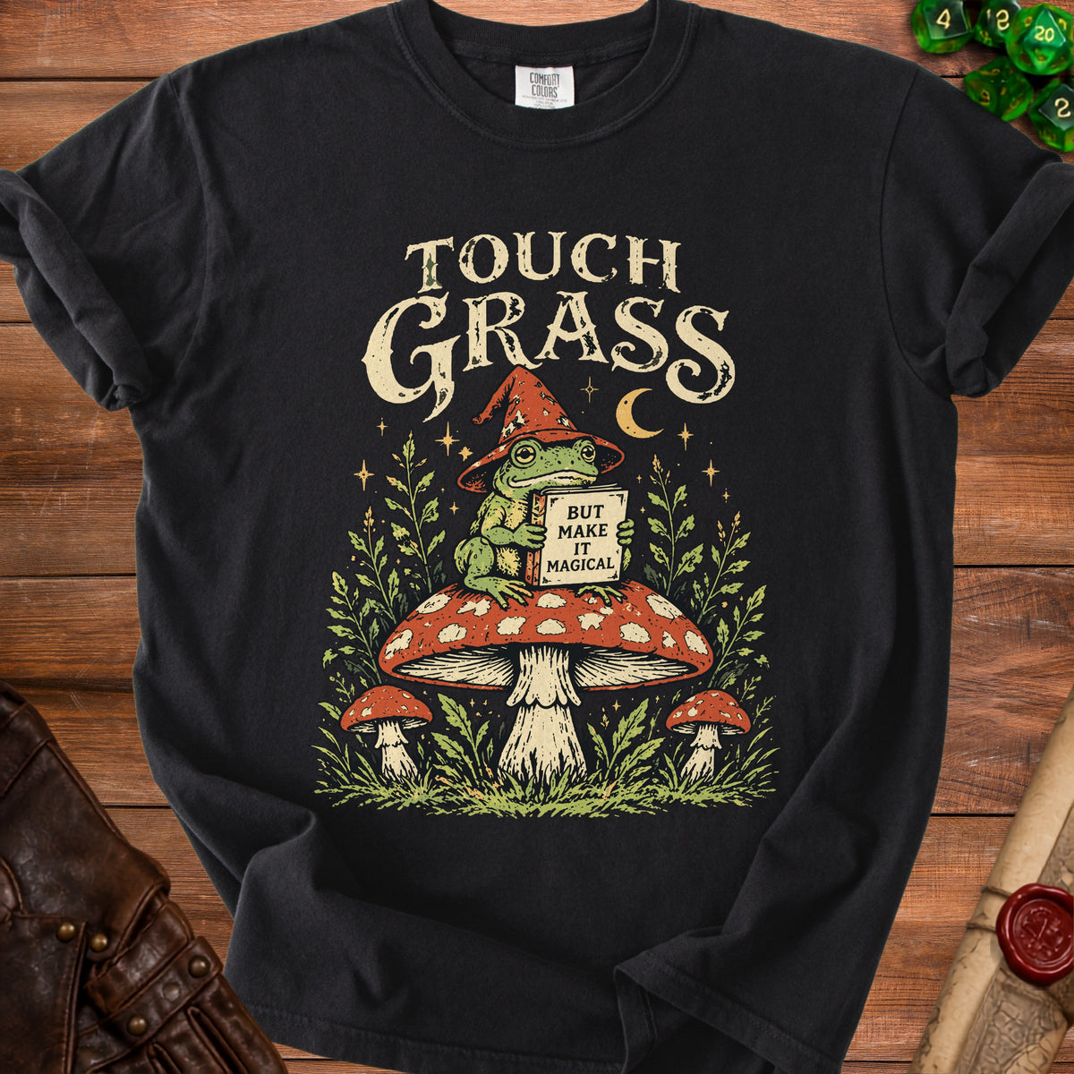 Black t-shirt with frog graphic reading "TOUCH GRASS BUT MAKE IT MAGICAL"