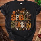 Black t-shirt with "Spell Season" text and Halloween motifs.